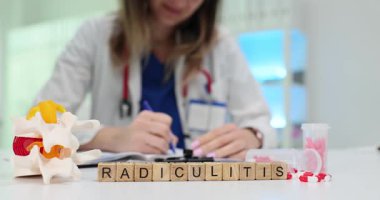 Tıbbi uzman, anatomik omurga modeli ve ağrı kesicilerin yakınına Radikülit önerileri yazar. Radkülit tedavi süreci
