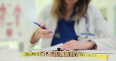 Kadın doktor, obeziteyle ilgili hasta kayıtlarını masadaki mezurayla karşılaştırır. Sağlık hizmetlerinde ağırlık yönetiminin önemi