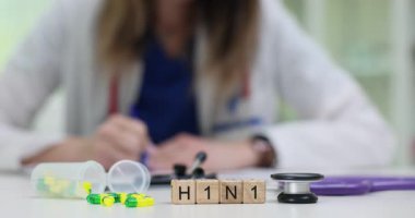 Kadın H1N1 domuz gribi için reçete yazıyor. Yanında da haplar ve steteskop var. Bulaşıcı hastalıkların yönetiminde tedavinin önemi