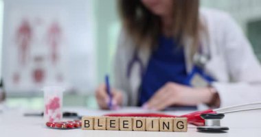Kadın doktor, hasta tıbbi geçmişinde, masada ilaçlarla oturan kanama hastalığıyla ilgili notlar yazıyor. Teşhis ve tedaviye odaklan