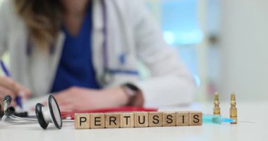 Kadın doktor, doktor masasına ahşap küplerin yanında stetoskop şırınga ve ampullerle birlikte Pertusis teşhisi koyan tıbbi raporlar yazıyor.