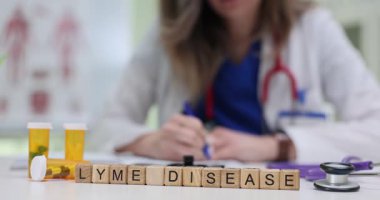 Kadın ilaç ve steteskopla çevrili Lyme Hastalığı tedavisi için reçete yazıyor. Uygun teşhis ve bakımın önemi
