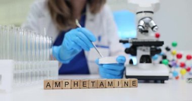 Tahta bloklarda amfetamin ve laboratuvarda doktor tozu kontrol ediyor. Kadın araştırmacı laboratuvarda uyuşturucu örneğinin kimyasal bileşimini analiz ediyor.