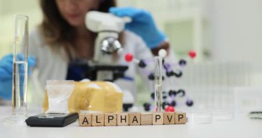 Tahta küplerde Alfa PVP ve laboratuvarda ekipmanı olan bir bilim adamı. Kadın asistan laboratuvarda mikroskopla uyuşturucu araştırması yürütüyor.