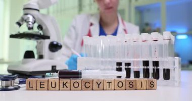 Bir tıp uzmanı laboratuvar ortamında mikroskop kullanarak lökositoz kan örneklerini dikkatlice analiz ediyor.