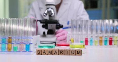 Samaryum, renkli test tüpleri ve detaylı analiz için mikroskop ile organize edilmiş bir bilimsel düzenek.