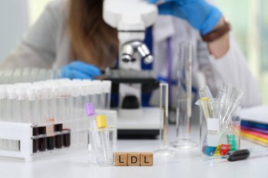 Çağdaş bir laboratuvar ortamında, kendini adamış bir bilim adamı LDL seviyelerini mikroskop altında dikkatle inceliyor.