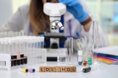 Bir laboratuar teknisyeni LDL ve HDL kolesterol seviyelerine odaklanarak kan örneklerini mikroskop altında analiz eder.