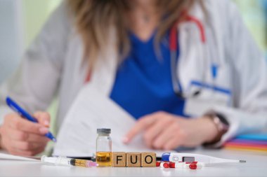 Bir sağlık çalışanı, kaynağı bilinmeyen bir ateşi kesin analiz için bir şişe ve malzeme kullanarak belgeliyor.