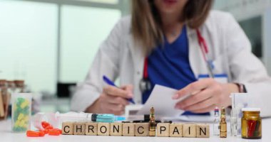 Kadın hekim hasta için uygun ilaçları seçer. Doktor Kronik Ağrı için tedavi planını belgeleyecek. Masaya yerleştirilmiş ilaç şişeleri.