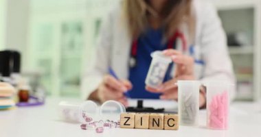Deneyimli kadın doktor bağışıklık sisteminin güçlendirilmesinde Çinko 'nun tahta bloklardaki önemini açıklıyor. Doktor reçete defterine ilacın adını yazmış.