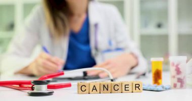 Doktor, masasında steteskop ve ilaçla kanseri heceleyen tahta küplere karşı reçete yazıyor. Hastanedeki ciddi hastalıklarla savaşmaya odaklan.
