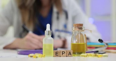 Tahta küplerle ilgili EPA mektupları ve doktor iş yerindeki takviyeler. Kadın doktor klinik ortamında Omega 3 yağ asidi reçetesi yazıyor.