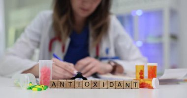 Tahta küplerin antioksidanı ve ilaç kapsülleri doktor masasında duruyor. Kadın hekim, hasta bakımında sağlık ve sağlığın önemini vurguladı