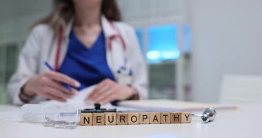 Kadın doktor nöropati tedavisi için reçete yazıyor. Haplar ve tahta küplerin yanında refleks çekiçle. Kadın klinik ortamında çalışıyor.