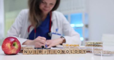Nutritionology 'deki kadın uzman elma ve tohumlarla çevrili klinikte notlar yazıyor. Sağlıklı beslenme ve sağlıklı beslenme