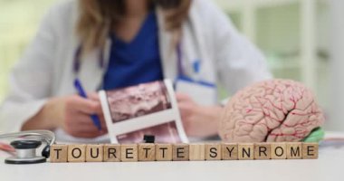 Bayan doktor beyin MR taraması görüntülerini analiz ediyor insan beyninin modeline yakın notlar yazıyor ve Tourette Sendromu teşhisi koyuyor. Beyin hastalıklarının tedavisi