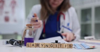 Doktor, tıp bürosundaki ahşap bloklardaki larenjiti incelemek için özenle çalışıyor. Gırtlak iltihabı tedavisini gösteren tıbbi konsept