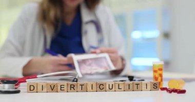 Kadın röntgen görüntülerinde Divertikülit teşhisi konan kolonoskopi sonuçlarını tutarken not alıyor. Hasta bakımı için masada tedavi hapları