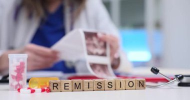 Kadın doktor ultrason taraması yapıyor. Klinikteki masanın yanındaki hapların yakınındaki tahta küplerde kelime remisyonu görülüyor. Umut ve iyileşmenin sembolü