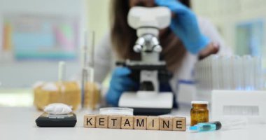 Tıbbi araştırmacılar Ketamin örneğini mikroskopla inceleyerek etrafını ilaç ekipmanlarıyla çevirmiş. Şırınga ilaçları laboratuvar ortamını öneriyor