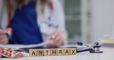 Klinikte ilaç ve steteskopla tahta küplerin üzerinde şarbon yazıyor. Kadın sağlık çalışanı bulaşıcı hastalık teşhisi yazıyor.