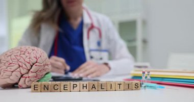 Tahta bloklarda kelime ensefaliti ve çalışan bir doktorun yanında insan beyni modeli. Kadın terapist nörolojik hastalıkların yenilikçi tedavisine odaklanıyor