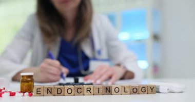 Çalışma masasındaki doktorlara karşı ahşap küplere endokrinoloji yaz. Doktor yoğun sağlık ortamında tedavi için reçete yazıyor