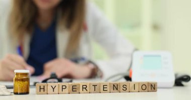 Tahta küplerle ilgili yüksek tansiyon metnini klinikte doktor yazmaya karşı kullan. Kadın doktor ilaç ve tansiyon monitörüyle tedavi için reçete yazıyor.