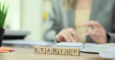 İş kadını masasında Startup varken küplerin yanında çalışarak masrafları hesaplıyor. Ayrıntılı mali strateji ve bütçe planlamasına yoğunlaşmak