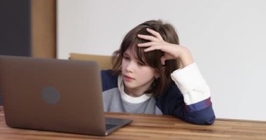 Liseli kız evdeki laptopta eğitici videolar izlerken kafasını masaya koyar. Kız çevrimiçi derslere katılmaktan ve ödevlerini yapmaktan sıkılmış ve yorgun hissediyor.