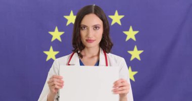 Kadın doktor Avrupa Birliği bayrağına karşı boş kağıt tutuyordu. Olumlu kadın doktor, AB 'nin sembol geçmişi hakkında bilgi verdi