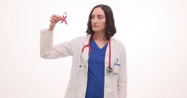 Steteskoplu kadın doktor beyaz arka planda kırmızı kurdele olduğunu söylüyor. HIV pozitif insanlarla dayanışma yavaş çekimde