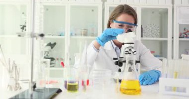 Mikroskop dalgalarına karşı modern laboratuarda selamlaşan kadın bilim adamı. Dost canlısı asistan kimya laboratuvarında araştırma ve analiz yürütüyor.