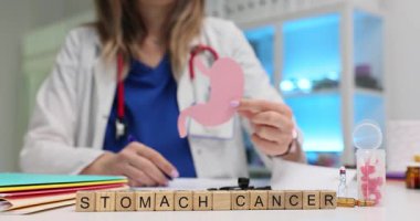 Tahta küplerle Mide Kanseri 'ni ve klinikte kağıt mideyi tutan doktoru yaz. Kadın doktor farkındalığın ve onkolojinin önemini gösteriyor