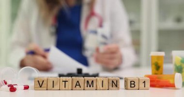 Doktor masasına tahta küplerden oluşan B1 vitamini yaz. Kadın hekim, sağlık hizmetlerinde genel sağlık ve sağlık için temel besin maddelerini reçeteler.