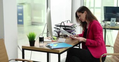 Deneyimli bir iş kadını masasında oturup yıllık raporunu dikkatlice gözden geçirir. Ciddi kadın, detaylara dikkat ederek finansal belgeler okuyor.