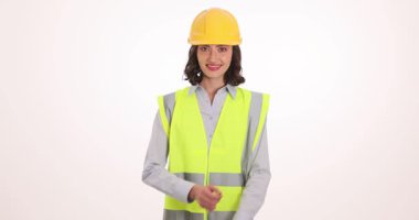Sarı şapka ve güvenlik yeleği giymiş kendine güvenen kadın mühendis beyaz arka planda gülümsüyor. Sanayi sektörlerinde işyeri güvenliği ve profesyonellik