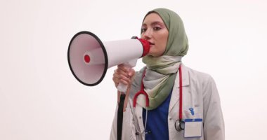 Tesettürlü kadın doktor hayati sağlık bilgilerini iletmek için megafonla konuşuyor. Kamu sağlık girişimlerini etkili bir şekilde bilinçlendirmek ve teşvik etmek