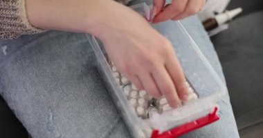 Kadınlar tıbbi ürünlerle çevrili kanepede otururken plastik ilk yardım çantasında ilaç ve hap arıyorlar. Evde tıbbi bakım senaryosu