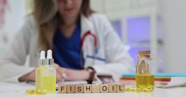 Kadın doktor, Fish Petrol 'ün yanında masa başında şişe ve kapsüllerle reçete yazıyor. Kadın, ek maddeler ve sağlık yardımlarıyla ilgili bilgi sunar