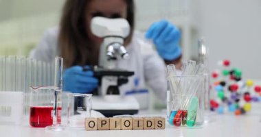 Koruyucu eldiven takan kadın bilim araştırmacısı laboratuvarda Opioidleri mikroskop altında inceliyor. Modern klinik ortamda tıbbi analiz
