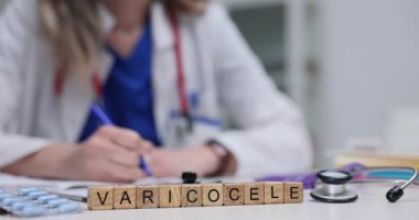 Kadın doktor, masasında Varicocele olan tahta küplerin yanında tedavi için reçete yazıyor. Erkek üreme sağlığına hitap etmenin önemi