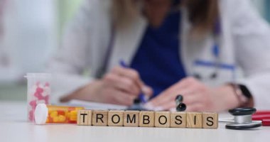 Tıp doktoru, ilaç ve steteskopla masada oturan küplere tromboz teşhisi koyuyor. Klinikteki sağlık ve hastalıklara odaklanın