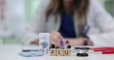 Kadın doktor, hastanede masasında ilaç ve steteskop ile çevrili olan küp tedavisine grip için reçete yazıyor. Hasta bakımı ve sağlık