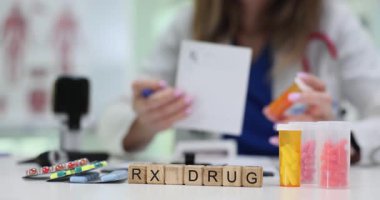 Tahta bloklardaki RX ilaçları, haplar ve klinikteki doktor. Pratisyen hekim hastaya hastanede verilen randevuda reçete yazar.