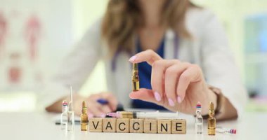Tahta küplere kelime aşısı ve masasında şişelerle doktor eli. Kadın doktor ilaç dozunu muayenehane ortamında hazırlar.