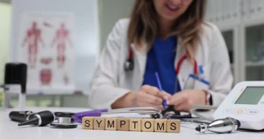 Doktor masasında tıbbi ekipman bulunan tahta blokların semptomları. Kadın doktor hasta raporunu yavaş çekimde teşhis araçlarının yanında verdi