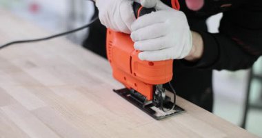 Yetenekli marangoz elektrikli yapboz kullanarak uzun tahta zemini dikkatlice keser. İnşaat işçisi yapboza düz bir çizgi üzerinde rehberlik ediyor. Yavaş çekim