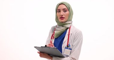 Tesettürlü Müslüman kadın doktor panoya notlar yazıyor. Genç Arap kadın beyaz hastane duvarında profesyonellik ve uzmanlık yayıyor.